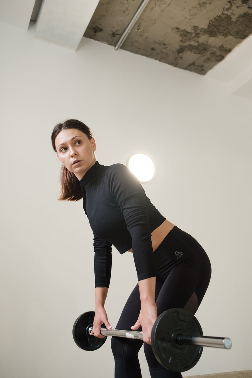 strong sportswoman doing bent over row with barbell in gym