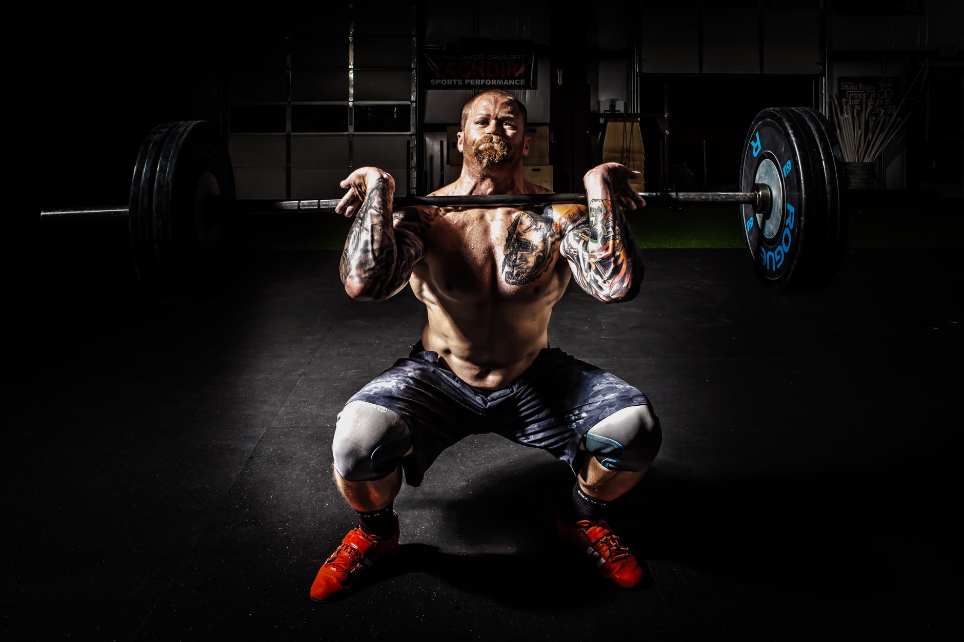 man in black shorts carrying adjustable barbells